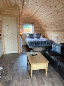 a room with a bed and a couch and a table at Pond View Pod 3 With Private Hot Tub - Pet Friendly -Fife - Loch Leven - Lomond Hills in Kelty