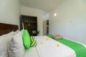 1 cama blanca grande con almohadas verdes y blancas en Kanasuk Self catering Apartments, en Baie Lazare Mahé