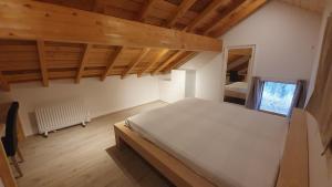 Cette chambre dispose d'un grand lit et de plafonds en bois. dans l'établissement La Ferme Les Digitales, à La Bresse