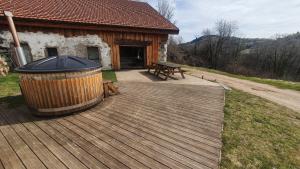 une terrasse en bois avec une table de pique-nique et un bâtiment dans l'établissement La Ferme Les Digitales, à La Bresse