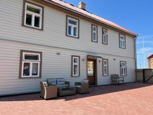 a large white house with chairs and a patio at Ostsee Apartments in Ventspils