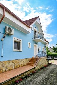 a blue house with stairs and a balcony at Kék Lagúna Vendégház in Balatonfüred