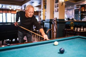 an older man playing a game of pool at Bud Gett Hostels in Groningen