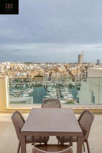 a table with chairs and a view of a harbor at Stunning 2BR penthouse with beautiful harbour view BY 360 Estates in Tal-Pietà