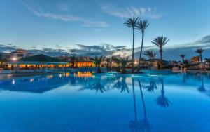 ミドゥンにあるDjerba Holiday Beachのヤシの木や建物のある大型スイミングプール