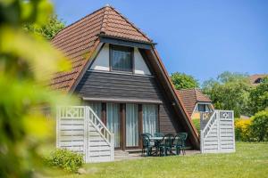 a house with a gambrel roof with tables and chairs at Ferienwohnpark Immenstaad am Bodensee Nurdachhaus Typ 8 NDT 111 in Immenstaad am Bodensee