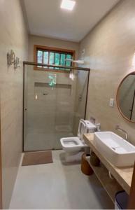 uma casa de banho com um WC, um lavatório e um espelho. em Cumuru pé na areia em Cumuruxatiba