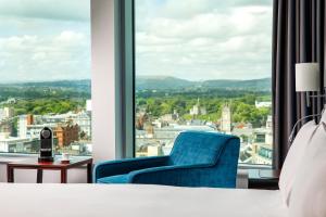 a bedroom with a blue chair and a large window at Radisson Blu Hotel, Cardiff in Cardiff