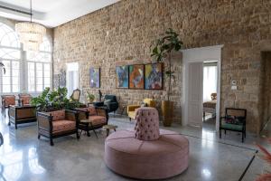 a living room with a couch and chairs and a brick wall at Dar Alice in Soûr