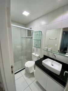 a bathroom with a toilet and a sink and mirror at Apto vista mar e pé na areia no Beach Way a 300m do Beach Park in Aquiraz