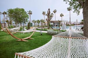 a park with hammocks in the grass next to a pool at Parmos Otel in Erdek