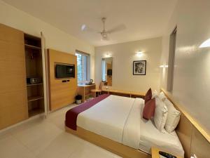 a hotel room with a bed and a television at Patria Suites in Rajkot
