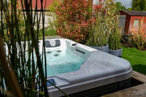 a bath tub in a yard with plants at Chalet, lodge, Cottage, avec spa au bord de l'eau in Prouilly