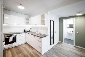 a kitchen with white cabinets and a sink at Limehome Budapest Mosonyi in Budapest +40 photos