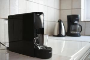 een zwart koffiezetapparaat met een glas op een aanrecht bij Fereniki's place in Gaios