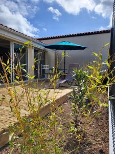 een patio met een parasol en een stoel op een terras bij Le Clos Saujonnais 2 in Saujon