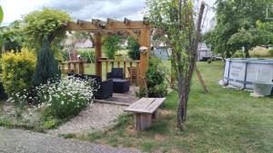 a wooden pergola with a bench in a yard at Chez David et Sonia in Éguzon-Chantôme
