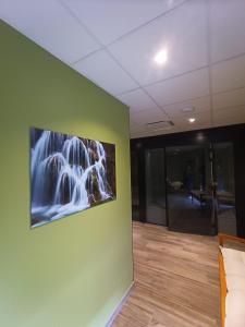 een groene muur met een schilderij van een waterval erop bij Akena Molinges - La Brocatelle in Saint-Claude