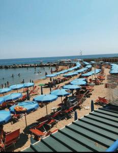 a beach with chairs and umbrellas and people in the water at Teatro Ariston, Elegante Appartamento Centrale in Sanremo