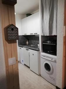 a kitchen with white cabinets and a washing machine at Studio RDC 4-5 pers pied des pistes in Chaillol
