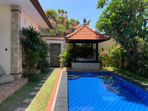 a swimming pool in front of a house with a gazebo at Villa Olga in Seminyak