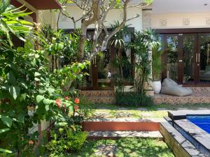 a garden with a house with a pool and plants at Villa Olga in Seminyak