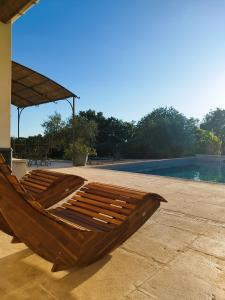 uma cama de madeira sentada num pátio ao lado de uma piscina em Domaine de l'Arbre Doré em Lèzan
