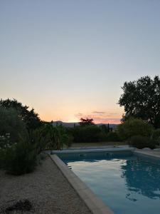 uma piscina com um pôr-do-sol ao fundo em Domaine de l'Arbre Doré em Lèzan