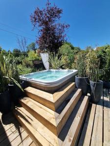 een hot tub bovenop een houten terras bij Chalet, lodge, Cottage, avec spa au bord de l'eau in Prouilly