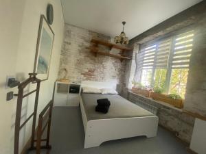 Un pequeño dormitorio con una cama blanca y una ventana en OLD CITY Loft, en Öskemen