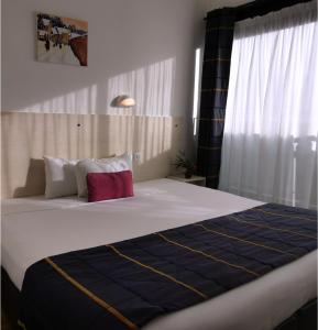 a bedroom with a large bed with a blue and white blanket at Logis Le Gavrinis in Baden