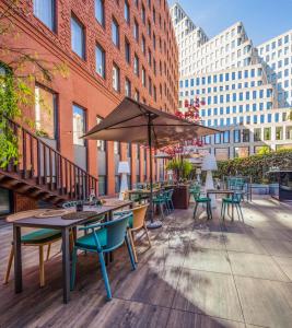 eine Terrasse mit Tischen, Stühlen und einem Sonnenschirm in der Unterkunft H10 Berlin Ku'damm in Berlin