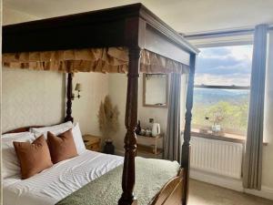 a bedroom with a canopy bed and a large window at The Mortal Man Inn in Troutbeck