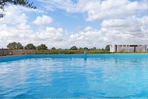 una gran piscina de agua azul con un edificio al fondo en Casa Arinto, en Palmela
