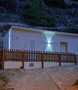 una casa bianca con una recinzione di legno di fronte di Cuocciu ri zuccuru a Scicli