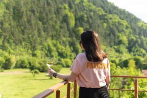 una donna in piedi su un balcone con un bicchiere di vino di Kleptuzaparts a Velingrad