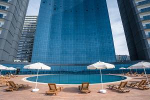 een zwembad met stoelen en parasols voor een gebouw bij Grand Bellagio Batumi Convention & Casino Hotel in Batoemi