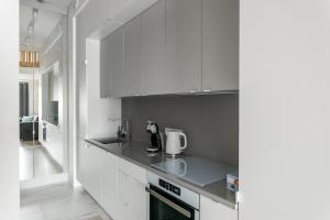 Premium Apartment in Kossak Residence في كراكوف: مطبخ بدولاب بيضاء وقمة كونتر