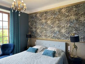 ein Schlafzimmer mit einem Bett mit blauen Kissen und einer Tapete in der Unterkunft Hôtel du Moulin in Allemagne-en-Provence