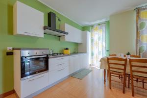 a kitchen with green walls and white cabinets and a table at La Rosa Gialla Bio Apartments & rooms in Barolo