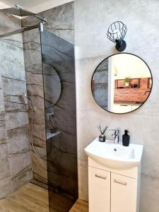 a bathroom with a sink and a shower with a mirror at Apartament Amelia1 in Świnoujście