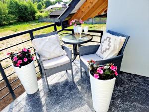 a patio with two chairs and a table and flowers at Apartament Amelia1 in Świnoujście