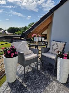 a patio with three chairs and a table with flowers at Apartament Amelia1 in Świnoujście