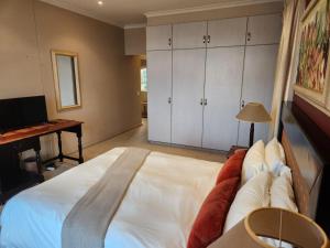 ein Schlafzimmer mit einem großen weißen Bett und einem Schreibtisch in der Unterkunft Pinnacle Point Golf Estate - Golf Villa 10-1 in Mossel Bay