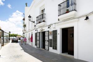 uma rua com edifícios brancos e pessoas andando pela rua em Casa Soumia em Vejer de la Frontera