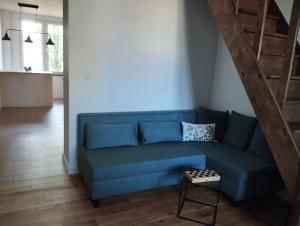 un sofá azul en una sala de estar con una escalera en Dwupiętrowy Apartament Ratusz Białystok en Białystok