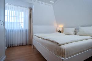 a white bedroom with a bed and a window at Villa am Meer in Westerland (Sylt)