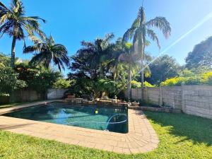 - une piscine dans une cour avec des palmiers dans l'établissement eagles inn, à Richards Bay