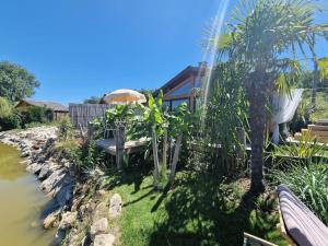 een tuin met een bank en een parasol naast een rivier bij Chalet, lodge, Cottage, avec spa au bord de l'eau in Prouilly