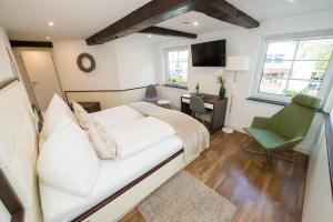 ein Schlafzimmer mit einem weißen Bett, einem Schreibtisch und einem grünen Stuhl in der Unterkunft Hotel zum Braunen Hirschen in Bad Driburg